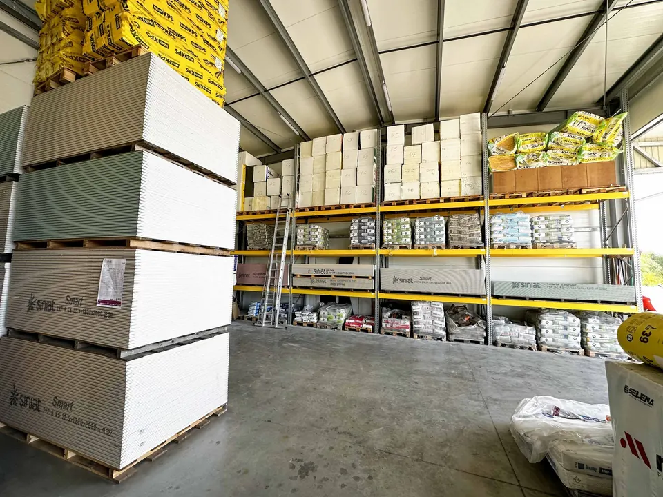 Magazyn SHOP BUDOWLANY — palety płyt gipsowych Siniat, styropian i wełna na regałach wysokiego składowania