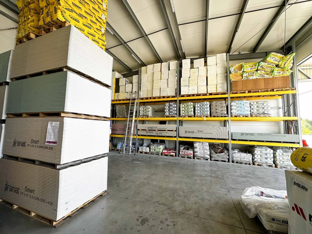 Magazyn SHOP BUDOWLANY: palety płyt gipsowych Siniat, styropian i wełna Isover na regałach
