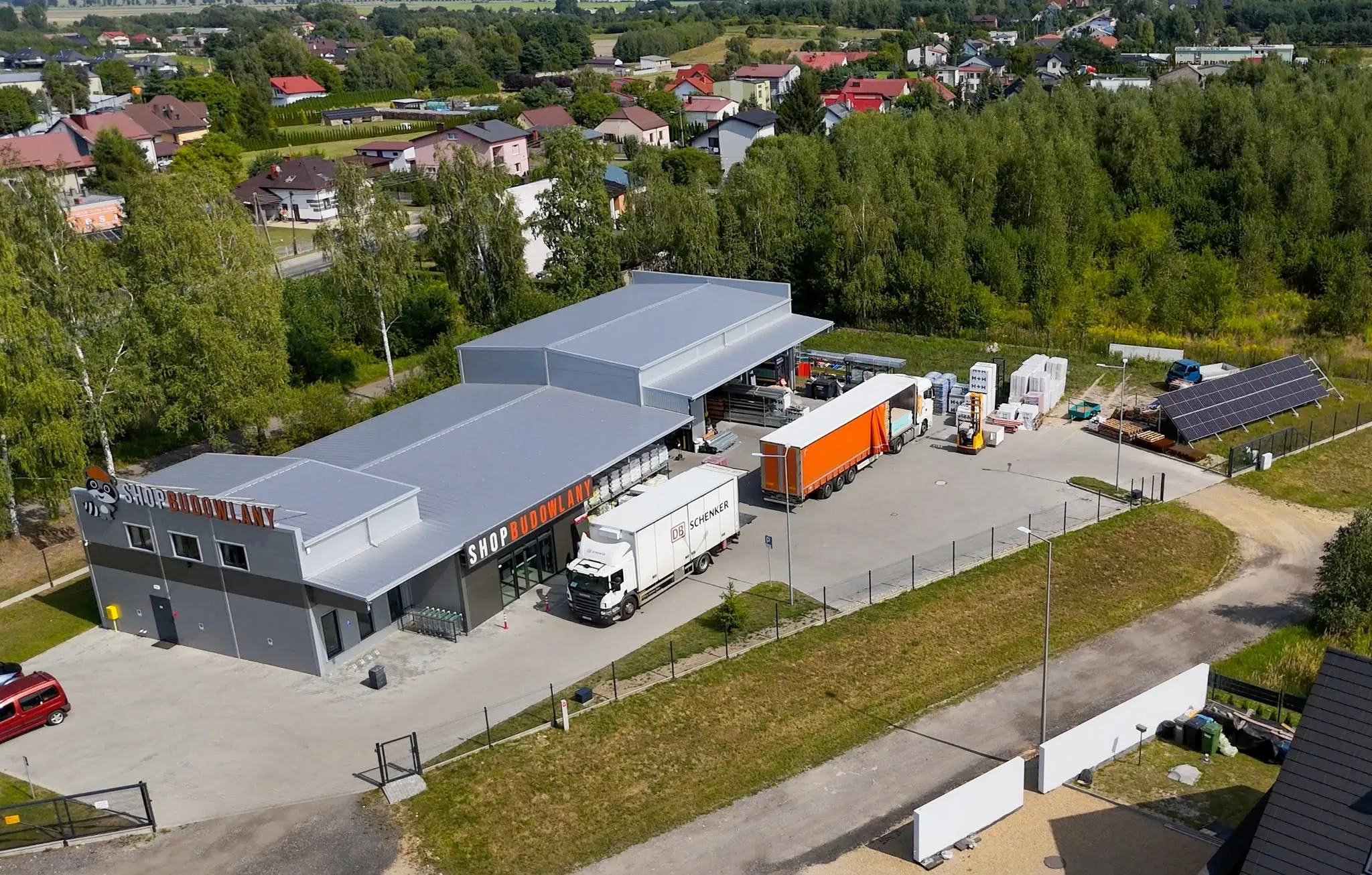 Skład SHOP BUDOWLANY w Kłobucku z lotu ptaka — hala magazynowa, plac i ciężarówki z materiałami